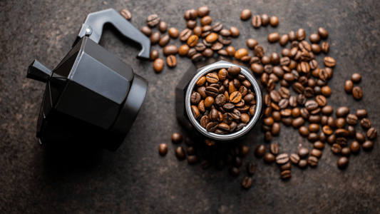 Ein Bialetti Espressokocher liegt auseinander gebaut auf dem Tisch, der Kessel ist mit Kaffeebohnen gefüllt.