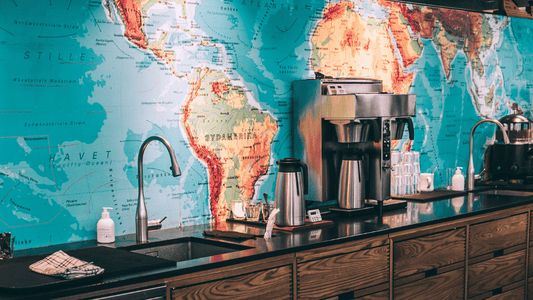 Eine Küchenzeile mit Kaffeemaschinen drauf, die Wand dahinter ist eine große Weltkarte mit Fokus auf dem Kaffeegürtel.