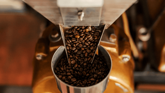 Kaffeebohnen fließen in den Behälter einer Kaffeemühle, wo sie gemahlen werden.